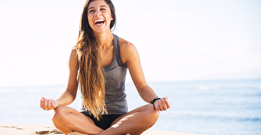 Young woman smiling during a meditation practice near the beach